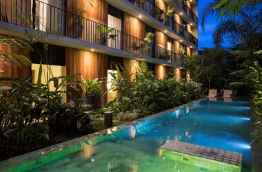 Beleuchteter Aussenpool am Abend vor der Holzfassade des Hotels Villa Amazonia in Manaus, Brasilien.