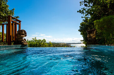 Blick aus dem Wasser eines Infinity-Pools auf die Küstenlandschaft von Natal.