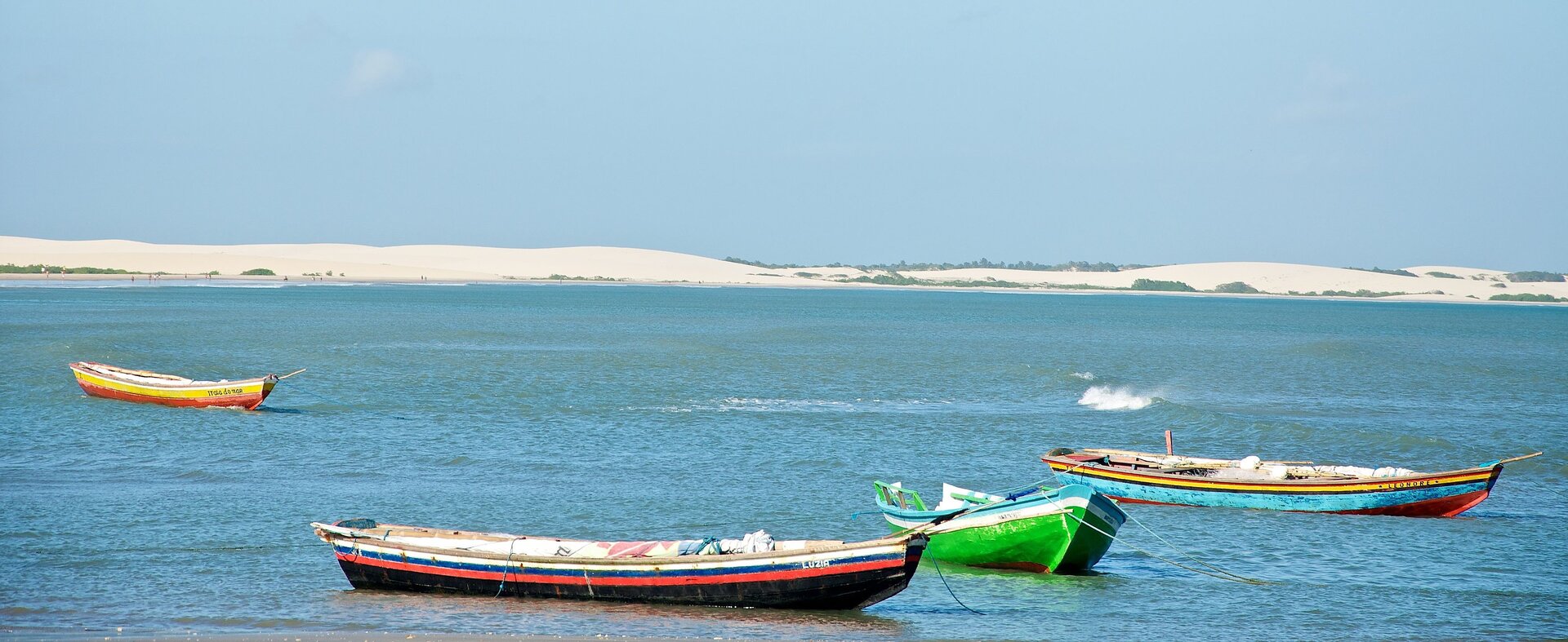 Bunte Fischerboote im Wasser von Jericoacoara, umgeben von den einzigartigen Dünenlandschaften der Region.