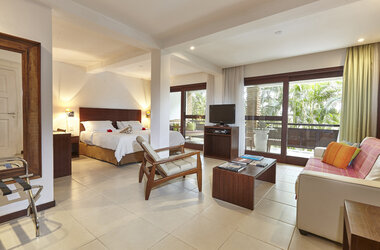 Master Suite im PortoBay Buzios mit Doppelbett, Sitzgruppe, TV und großem Balkonzugang mit Blick ins Grüne.