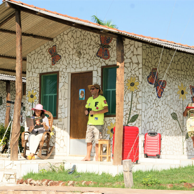 Gäste entspannen vor einem bunt verzierten Bungalow im Hotel UeSo Pantanal, Brasilien.