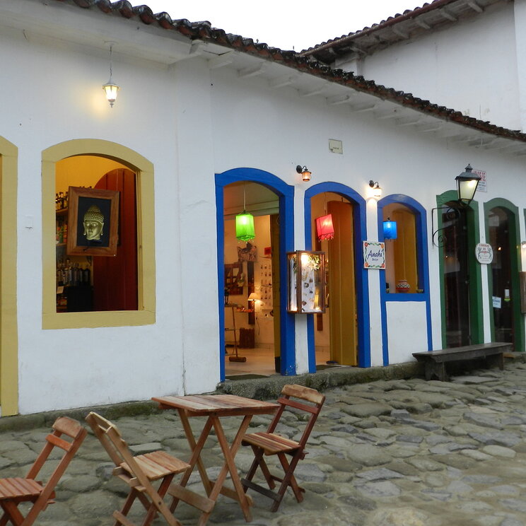 Bunte Geschäfte und Cafés in Paraty, Brasilien, mit einladenden Sitzgelegenheiten im Freien und einer charmanten Fassade, die die koloniale Architektur der Stadt widerspiegelt.