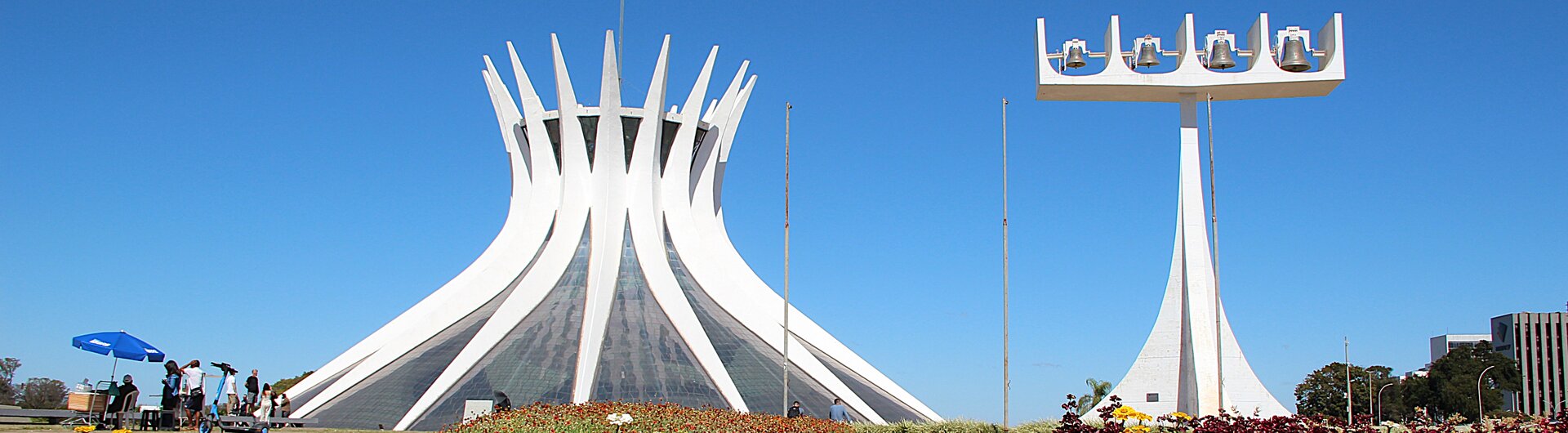 Kathedrale von Brasília hinter einem bunten Blumenbeet unter blauem Himmel in Brasilien.