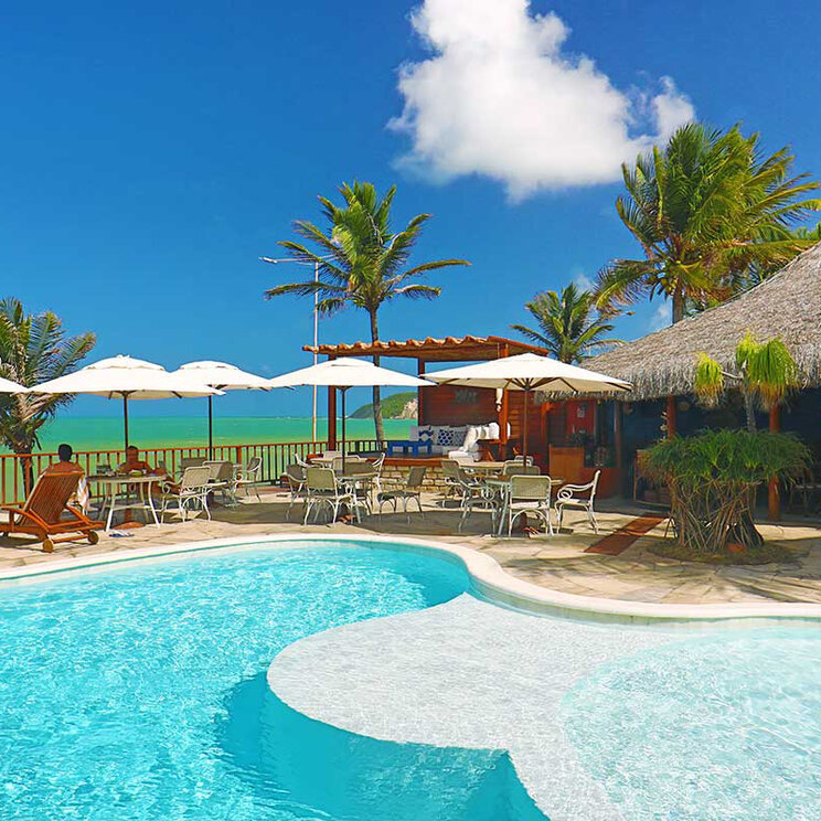 Poolbereich des Manary Hotels mit Sonnenschirmen, Liegen und Meerblick in Natal, Brasilien.