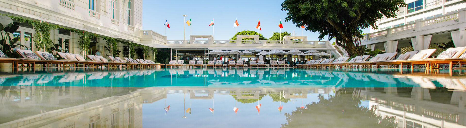 Großer Außenpool im Innenhof des legendären Luxushotels Copacabana Palace in Rio de Janeiro, Brasilien, mit weißen Sonnenliegen und Blick auf die historische Palastfassade.