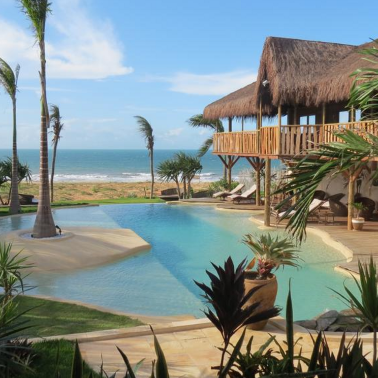 Das Hurricane Hotel in Jericoacoara bietet einen idyllischen Poolbereich mit Blick auf das Meer, umgeben von Palmen und tropischen Pflanzen, der zum Entspannen einlädt.