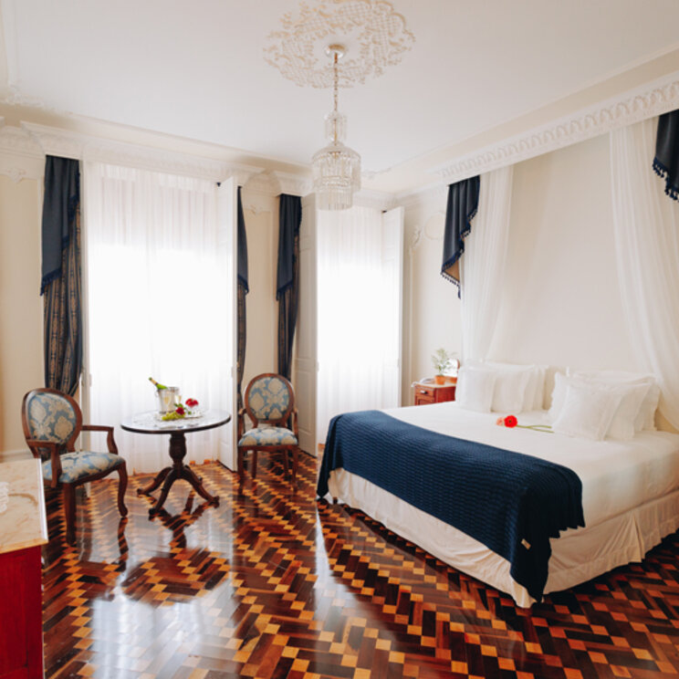 Helles Schlafzimmer mit dunklem Parkett, Kronleuchter und weißem Himmelbett in Florianopolis