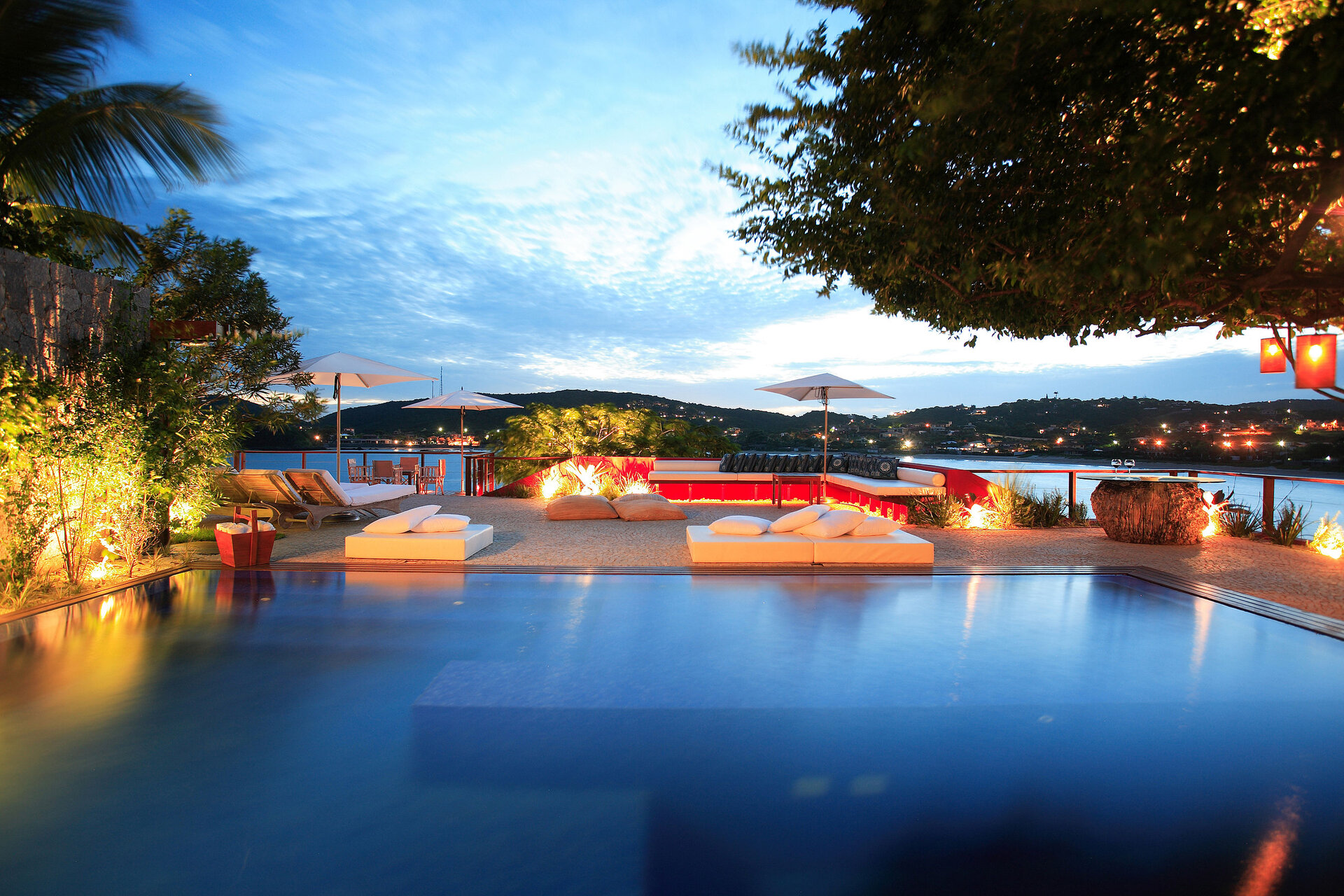 Der Pool im Hotel Insolito in Búzios bei Abenddämmerung, elegant und modern gestaltet, bietet einen herrlichen Blick auf die umliegende Landschaft und das Meer, umgeben von stilvollen Liegeflächen.