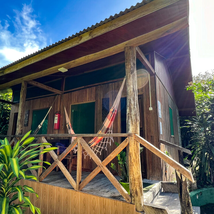 Aussenansicht eines Holzbungalows mit Veranda und Haengematte im Amazon Village, Brasilien.