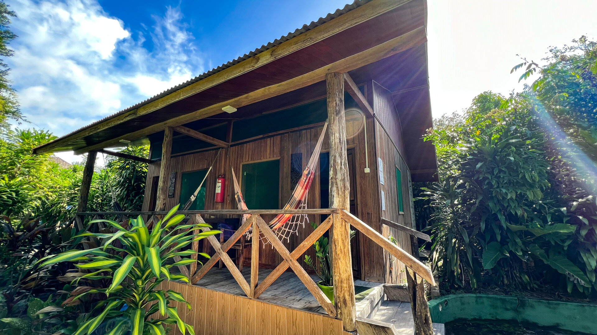 Aussenansicht eines Holzbungalows mit Veranda und Haengematte im Amazon Village, Brasilien.