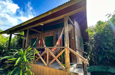Aussenansicht eines Holzbungalows mit Veranda und Haengematte im Amazon Village, Brasilien.