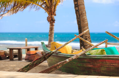 Traditionelles Fischerboot mit bunten Kissen als Sitzgelegenheit am Sandstrand des Nannai Resort, Brasilien.