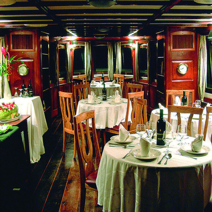 Elegantes Speisezimmer der Tucano-Kreuzfahrt mit stimmungsvoller Beleuchtung und klassischem Holzdekor, für ein stilvolles Abendessen auf dem Amazonas.