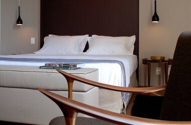 Modernes Doppelzimmer mit dunkler Akzentwand, weißen Kissen und Designer-Hängeleuchten im Zank Hotel.