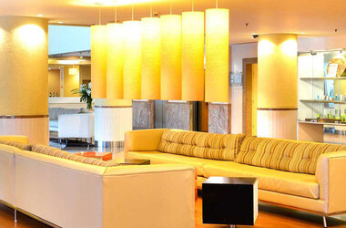 Moderne Hotellobby im Pestana Sao Paulo mit hellen Sofas und markanten gelben Zylinderlampen in Brasilien.