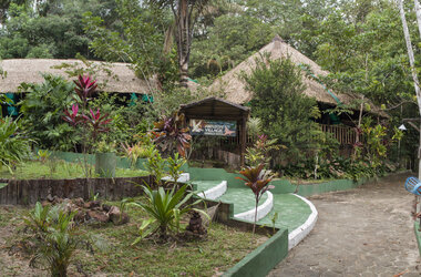 Tropischer Garten und Eingangsbereich mit Hinweisschild der Amazon Village Lodge in Brasilien.