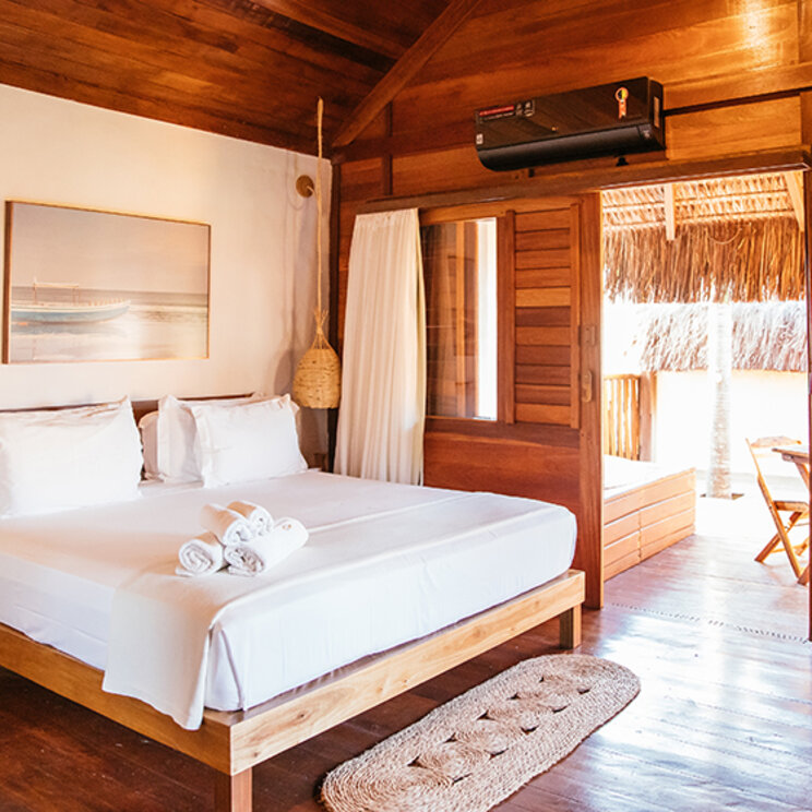 Rustikales Schlafzimmer im Bangalo Luxo mit Holzinterieur, Klimaanlage und Terrasse im Hurricane Jeri Hotel.