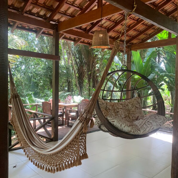 Hängematte und Hängesessel unter Holzdach der Amazon Premium Lodge im Amazonas, Brasilien, umgeben von tropischer Vegetation.