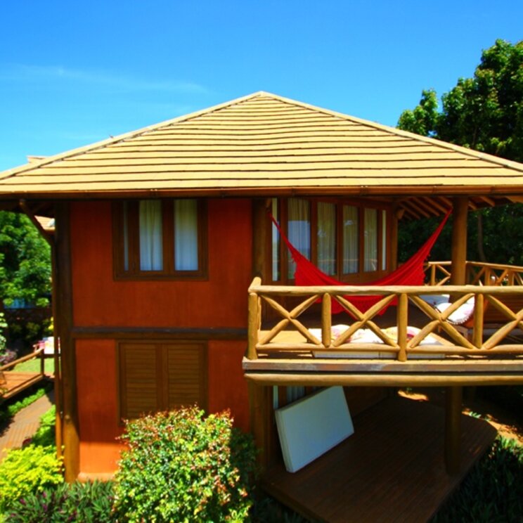 Zweistöckiger Holz-Bungalow mit Balkon, roter Hängematte und Palmen in der Pousada Triboju, Fernando de Noronha, Brasilien.
