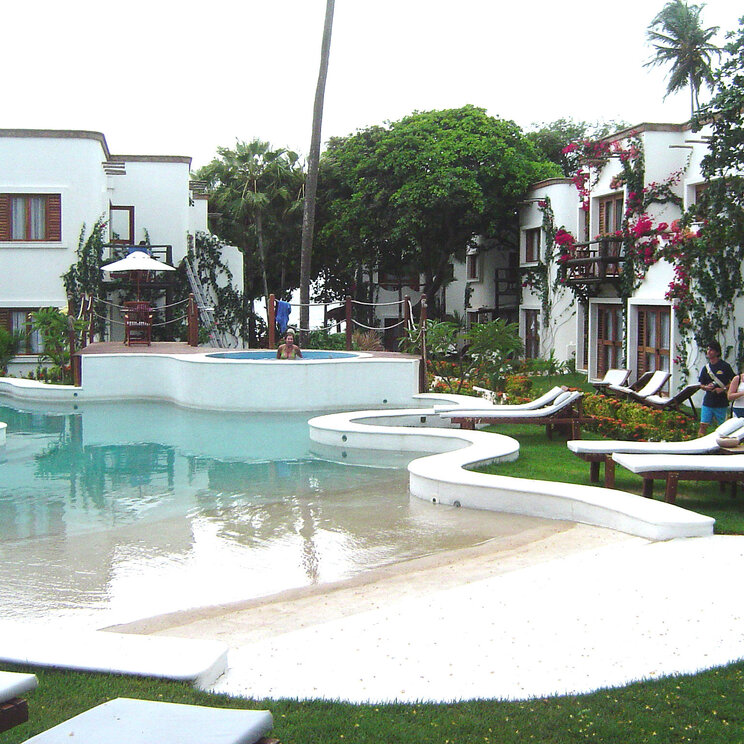 Ein Resort mit weißen Gebäuden und einem geschwungenen Pool, umgeben von Liegestühlen und tropischen Pflanzen im My Blue Hotel in Jericoacoara, Brasilien