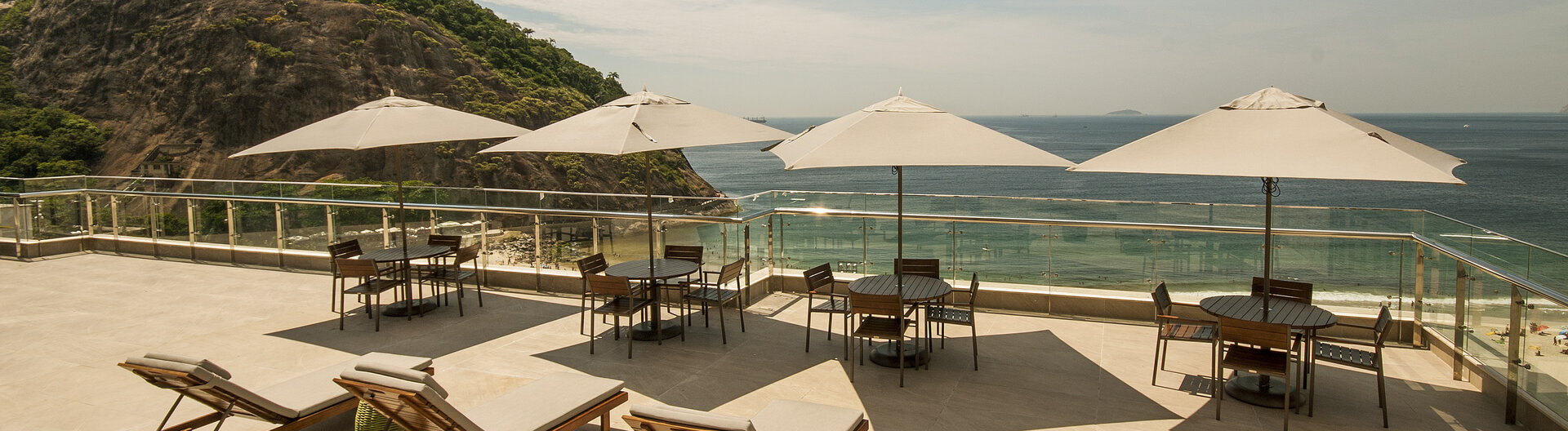 Dachterrasse mit Sonnenliegen, Schirmen und Sitzgruppen vor der Kueste von Leme in Rio de Janeiro, Brasilien.