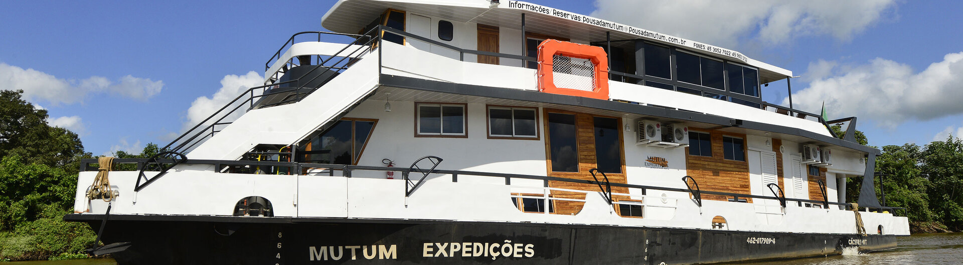 Mutum-Expeditionsboot auf dem Fluss im Pantanal, Brasilien, bei strahlend blauem Himmel.
