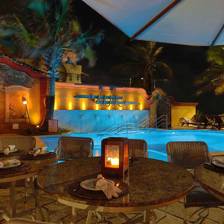 Gedeckte Tische am beleuchteten Pool bei Nacht, Manary, Natal, Brasilien.